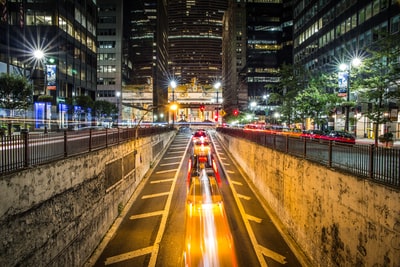 时间流逝摄影的车辆将混凝土路面周围高层建筑在夜间
